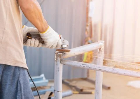 Worker use electric grinding pole head to smooth in factory. Stock Photos