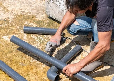 Worker use electronic grinding disk blade cutting grey pipe. Stock Photos