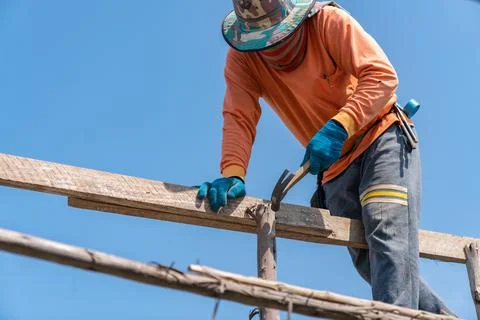 Worker use hammer hit nails on scaffolding for support second floor. Stock Photos