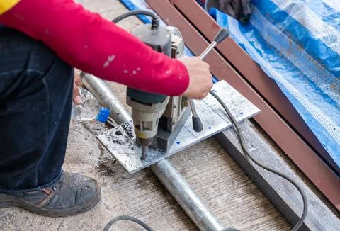 Worker use magnetic drill drilling metal plate. Stock Photos