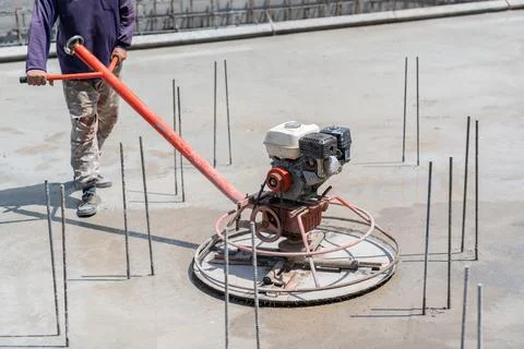 Worker use Power trowel machine on wet concrete. Stock Photos