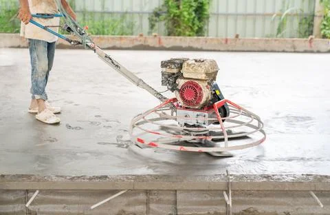Worker use scrub floor machine to polish surface new concrete floor. Stock Photos