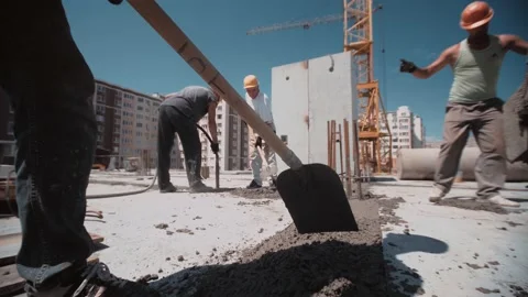 Worker use shovel to level concrete on foundation of house Stock Footage 143216970