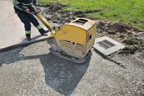 Worker use vibratory plate compactor at road construction site 库存照片