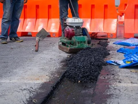 Worker use vibratory plate compactor compacting asphalt at road 写真素材