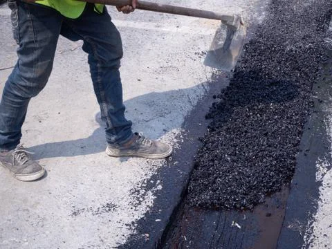 Worker use vibratory plate compactor compacting asphalt at road Stock Photos