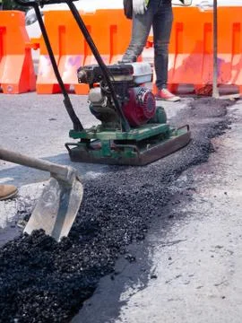 Worker use vibratory plate compactor compacting asphalt at road 写真素材