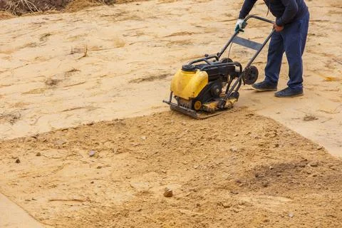 Worker in use vibratory plate compactor for path construction. Plate compactor Photos
