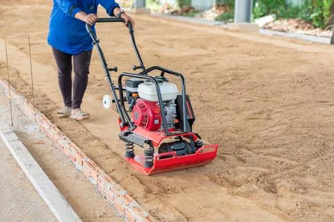Worker use vibratory plate machine compactor for construction compacting. Stock Photos