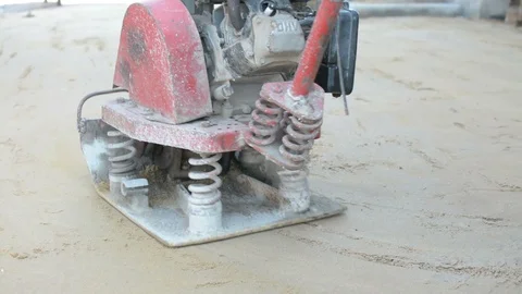 Worker use vibratory plates seals the base sand Stock Footage 98735009