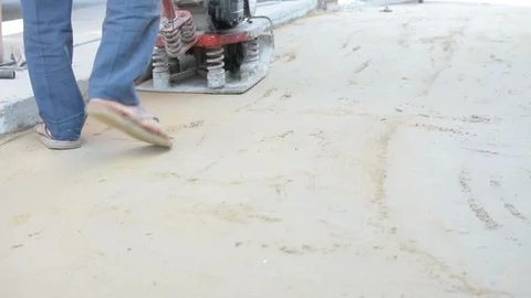 Worker use vibratory plates seals the base sand Stock Footage 98747272
