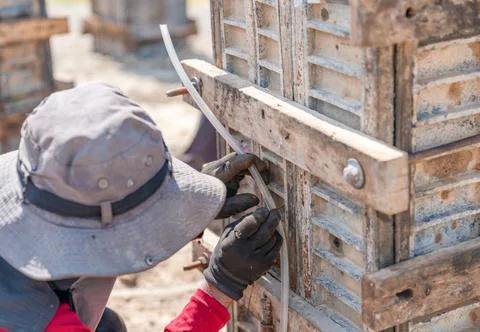 Worker used a water level to align the foundation posts. Stock Photos