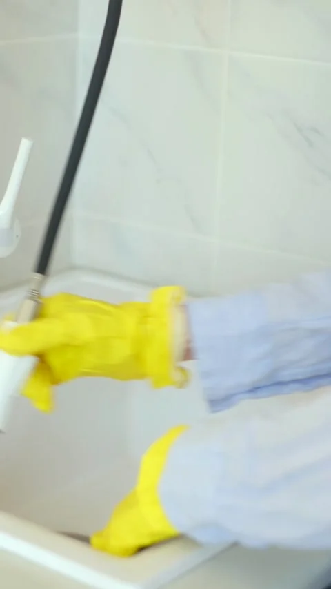 Worker uses adjustable tap removing detergent from sink surface Stock Footage 312985562