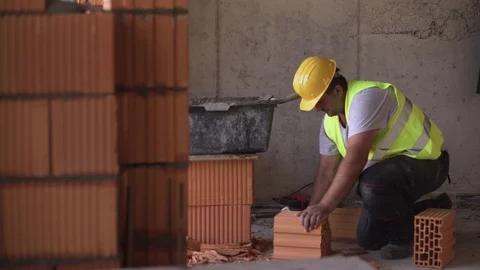Worker uses adze like cutting tool to slicing brick on specific measure, masonry Video stock 94533216