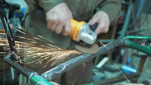A worker uses a angle grinder on a bicycle to grind the frame. Stock Footage 317499148