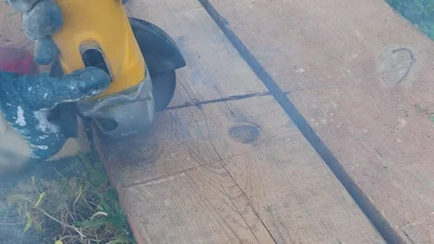 A worker uses an angle grinder to cut wood planks with a lot of smoke. FullHD Vídeo Stock 139198189