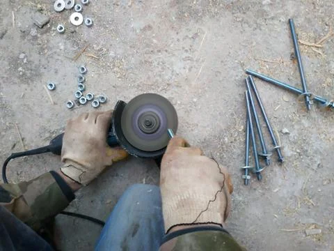 The worker uses an angle grinder to sharpen the bolts, a close-up plan Stock-Fotos