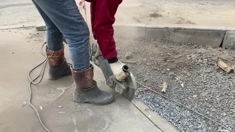 A worker uses an asphalt cutting machine to repair a road Stock Footage 320249624