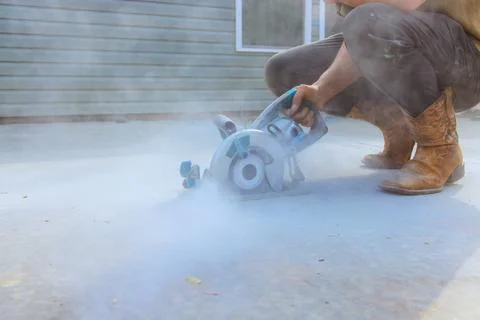 Worker uses circular saw on construction site while dust smoke rise in air Stock Photos
