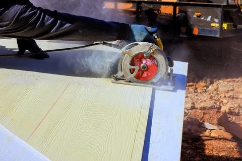 Worker uses circular saw to cut wood on construction site Stock Photos