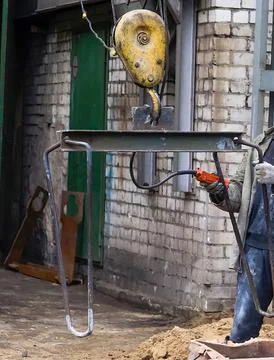 Worker uses crane hook to safely lift construction materials in an urban envi Foto stock