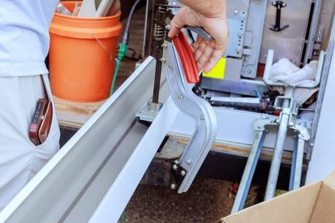 Worker uses cutting hole tool to gutter metal parts in truck at job site Fotos de archivo