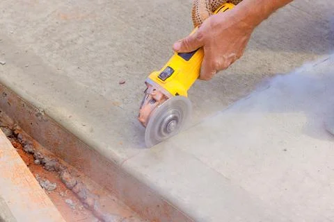 Worker uses cutting tool on concrete surface at construction site Stock Photos