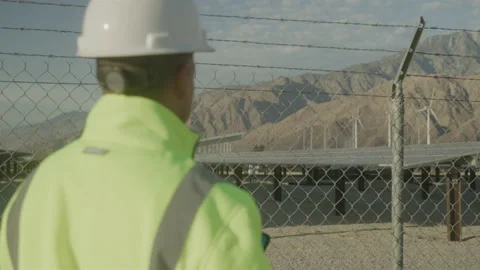 Worker Uses Device on Green Energy Desert Job Site with Distant Mountains Stock Footage 211869216