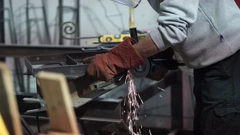 Worker uses disc grinder on metal bars in workshop Stock Footage 81859673