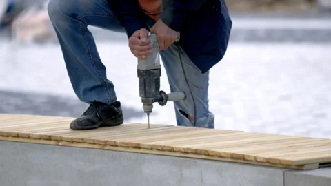 Worker uses drill to create holes in bench wooden planks Stock Footage 246666644