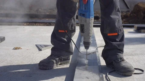 Worker uses electric drill to make hole for screw. House foundation construction Stock Footage 118990819