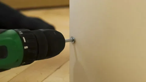 Worker uses electric screwdriver to twist screw into side wall Stock Footage 304396297