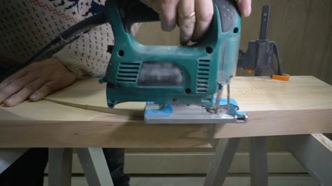 Worker uses fretsaw for cutting piece of wood Stock Footage