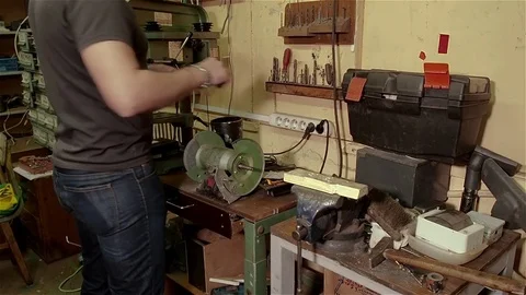 Worker uses grindstone to repair drill in old workshop Stock Footage 70897412
