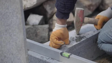 Worker uses hammer and level to build stone wall Video stock 332750750