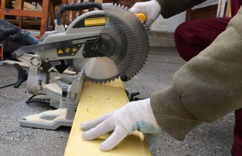 A worker uses a hand-held circular saw to saw a board Stock Photos