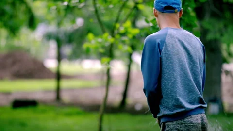 Worker uses hose to spray water about city park lawn Stock Footage 246053781