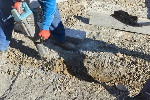 Worker uses jackhammer tool to dig in construction site Stock Photos