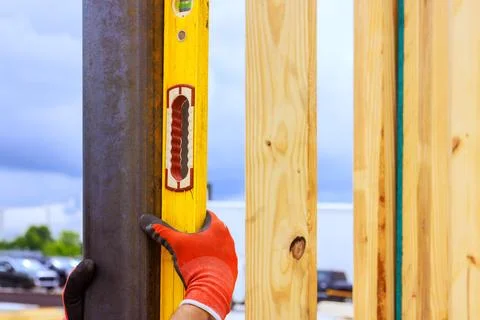 Worker uses level tool to ensure vertical alignment of wooden frame at Stock Photos
