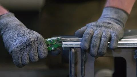 Worker uses locking pliers on steel to fabricate custom metalwork with hands Stock Footage 125180403