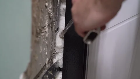 Worker uses a mounting gun to fill cracks with polyurethane foam Video stock 264469975