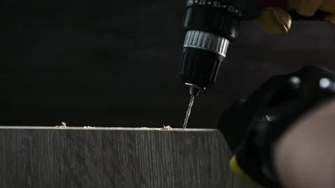 Worker Uses a Power Drill to Make a Hole in a Wooden Board Indoors Stock Footage 339085242