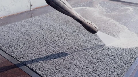 Worker uses pressure washer to clean textured surface in industrial setting Vídeos de archivo 345678817