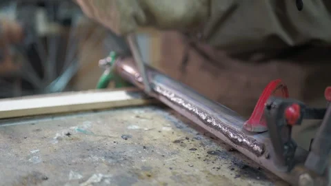 A worker uses a round file to remove slag from a weld on a pipe. Stock Footage 317499103