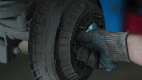 Worker uses socket wrench to tighten bolts on axle hub. Stock Footage 344232207