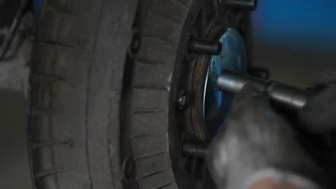 Worker uses socket wrench to tighten bolts on axle hub. Stock Footage 344232231