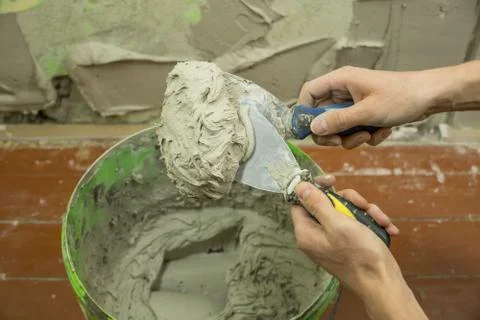 A worker uses a spatula to get a solution of the cement mixture.The master pu Stock Photos