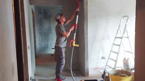 Worker uses tool to smooth wall surface in construction area during renovation p Stock Footage 325328863