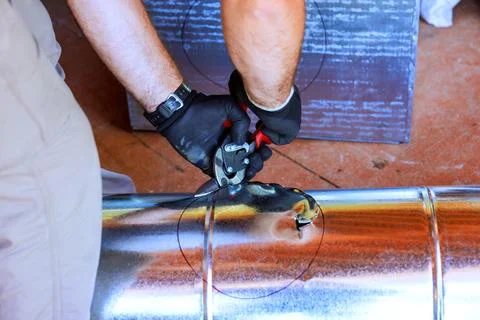 Worker uses tools to cut metal pipe in workshop during metal duct assembly Stock Photos