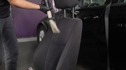 A worker uses a vacuum cleaner to remove dirt from the back of the seat. Video stock 247153344